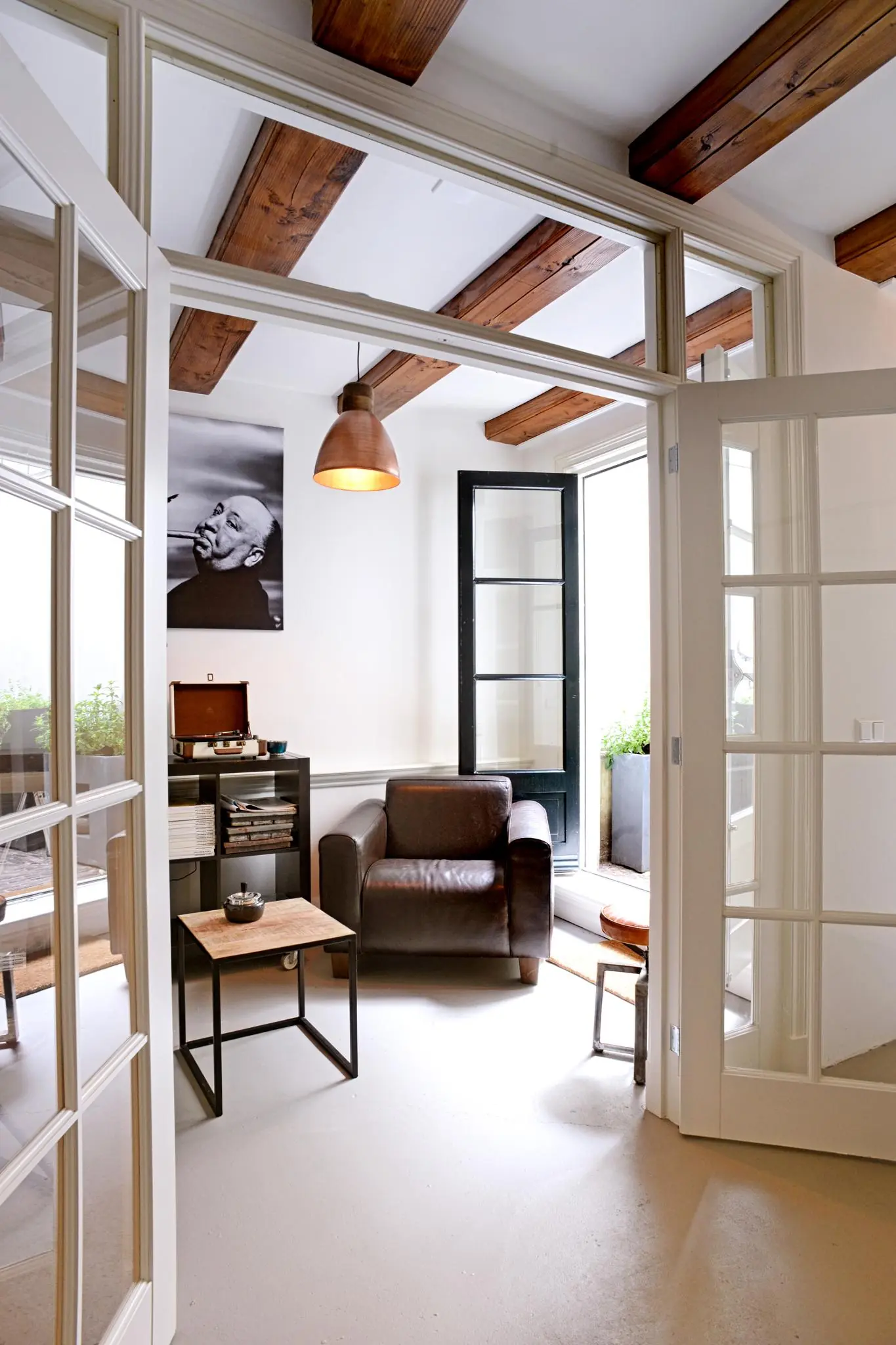 Stijlvol ingerichte zithoek met leren fauteuil, platenspeler en openstaande deuren in een woning aan de Nieuwe Kerkstraat.